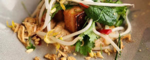 A close up of a pork belly dish with bean sprouts and coriander